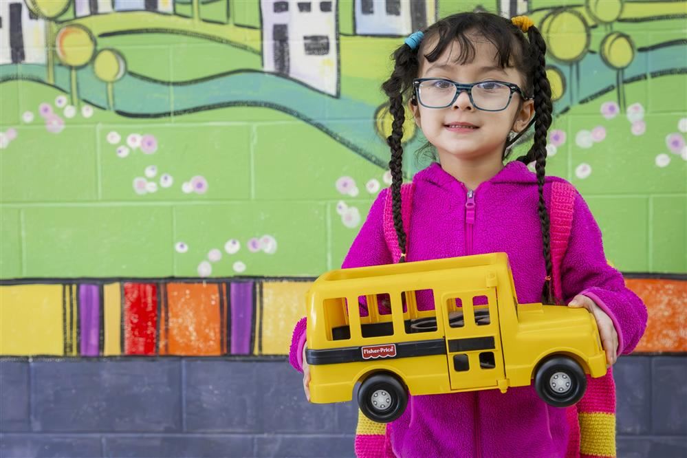 Girl holding plastic school bus