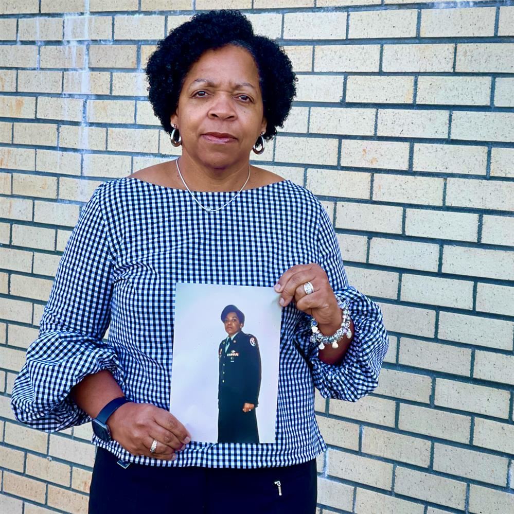  image of Susan Heaggans holding a photo of herself in uniform