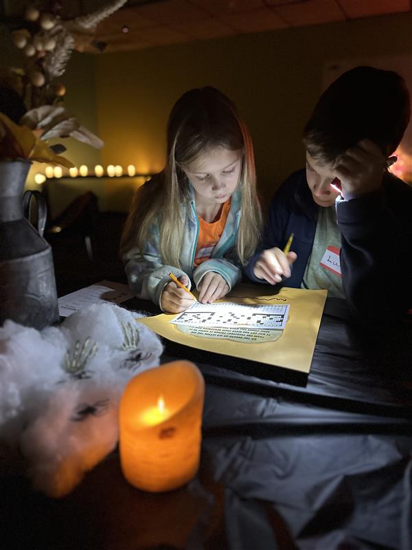 girl and boy completing crossword puzzles by flashlight